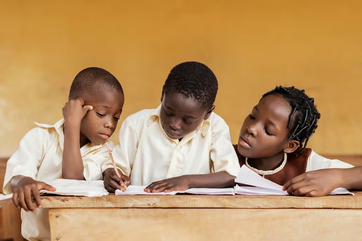 Three schoolchildren learning together at a classroom desk