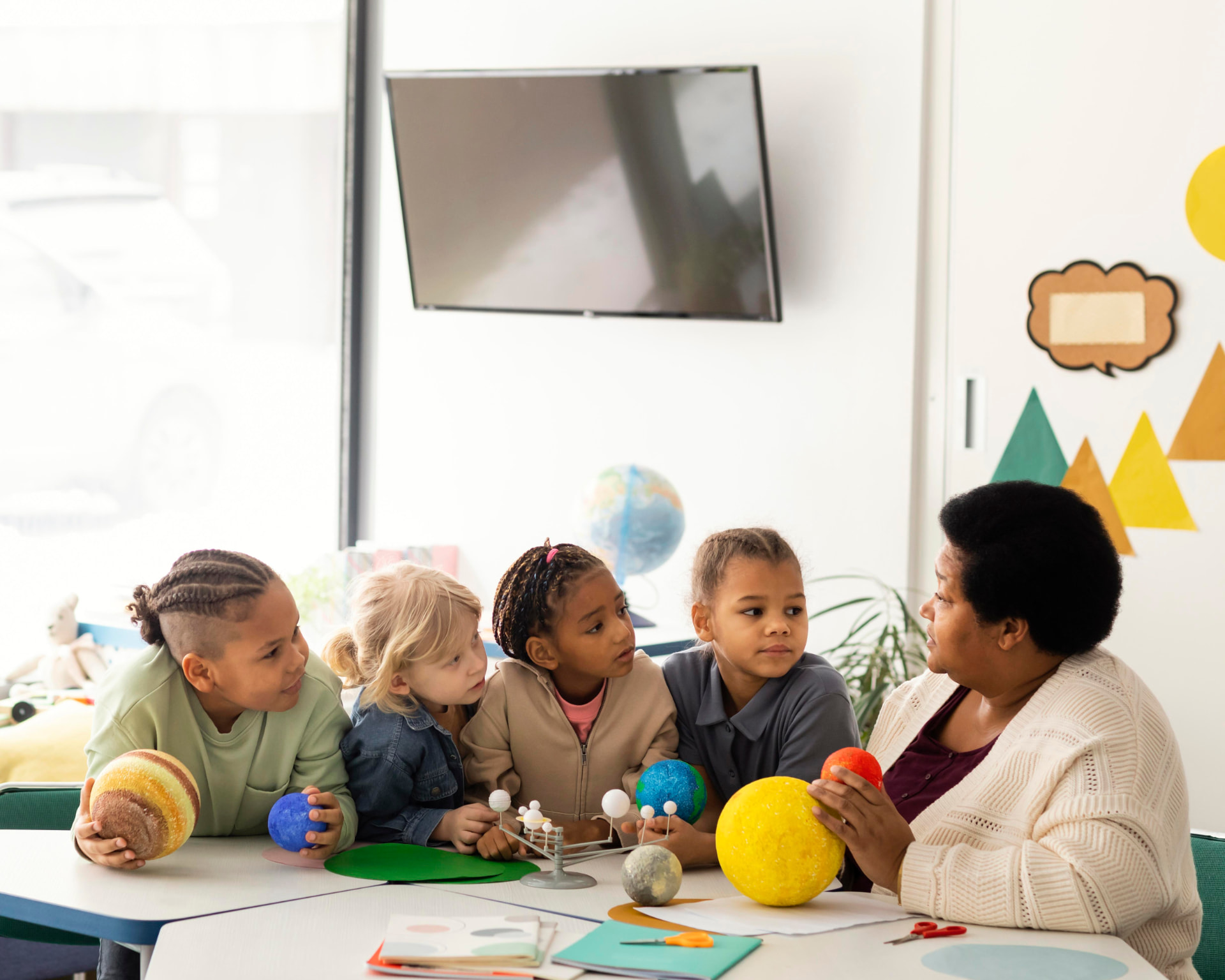 A teacher guiding young learners through a practical lesson